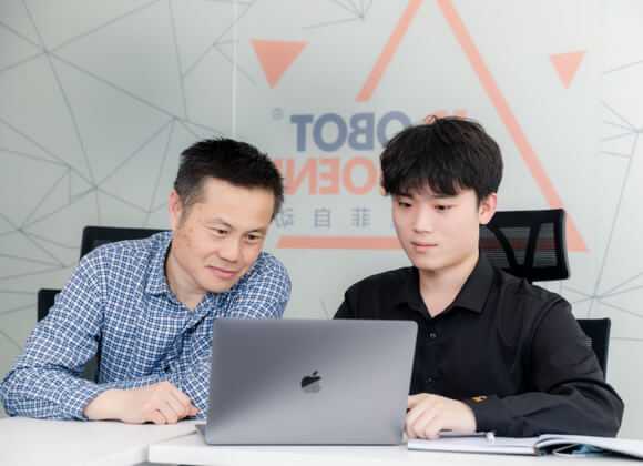 2 men are looking at the computer during the meeting