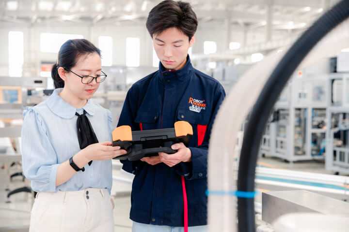 2 people are discussing beside the robot