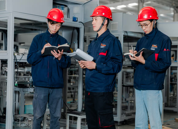 3 men with red helmets are taking notes in the workshop